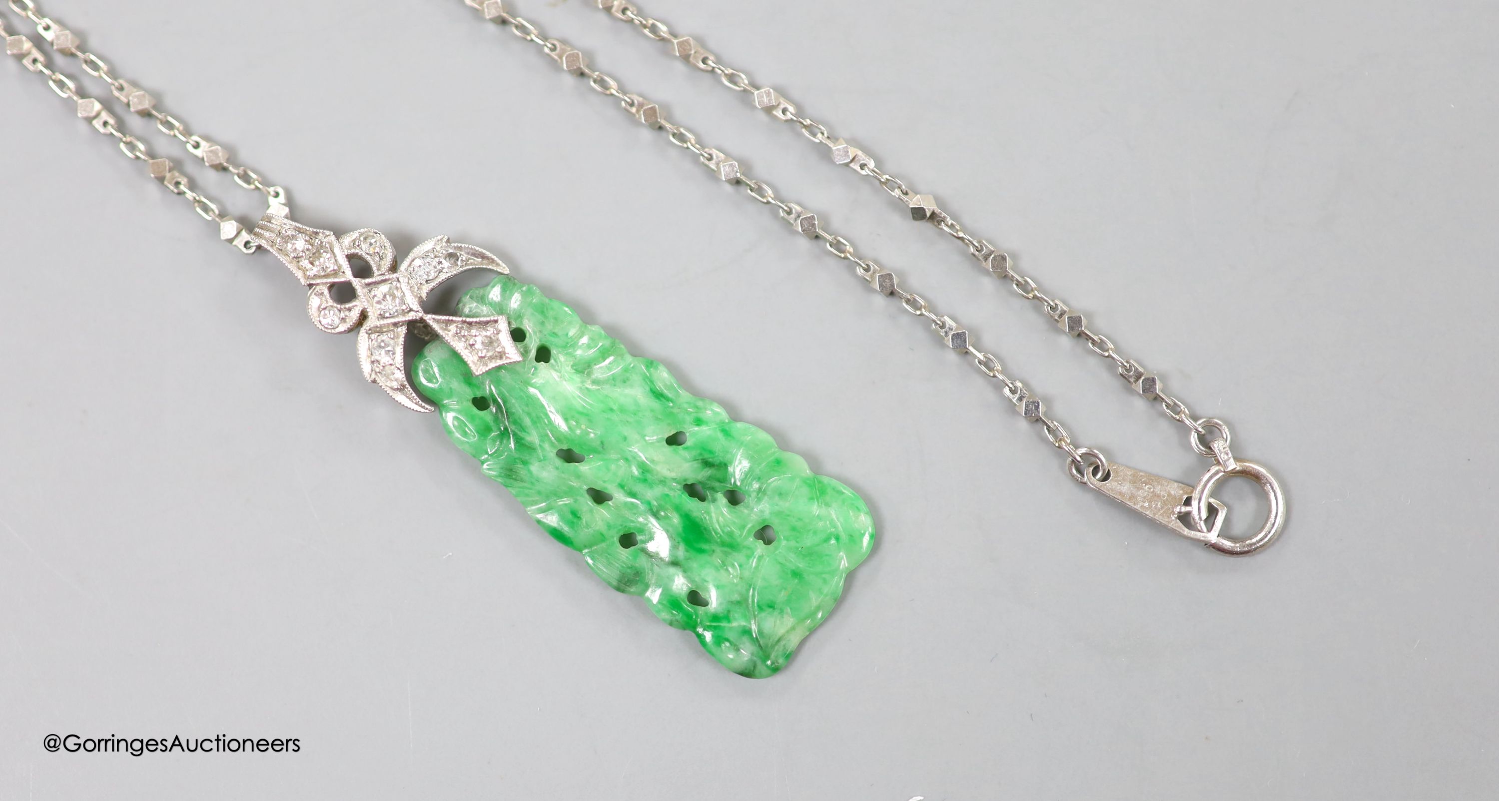 A 1920's white metal and diamond mounted carved jade pendant, numbered 'G 320 1', 4cm, on a platinum fancy link chain, 40cm, gross weight 7.6 grams